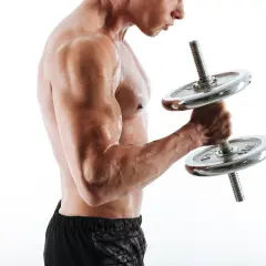 Mężczyzna ćwiczy biceps z hantlem. Widać napięte mięśnie i pot na skórze.