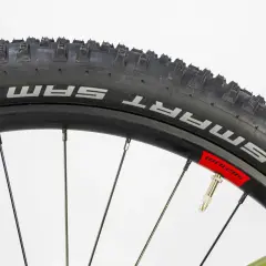 Koło rowerowe z oponą Schwalbe Smart Sam i wentylem. Widać fragment dętki przez przezroczystą osłonkę wentyla.