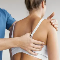 Fizjoterapeuta bada napięcie w obrębie powięzi na plecach pacjentki, oceniając jej stan.