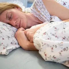 Kobieta śpi spokojnie, otulona pościelą w kwiaty. Czyżby odkryła sekret, jak szybko zasnąć?