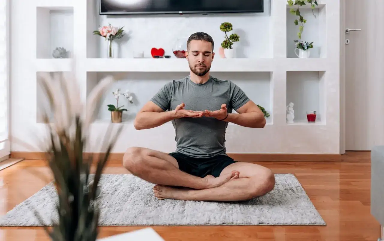 Mężczyzna w pozycji lotosu praktykuje jogę kundalini w domu.